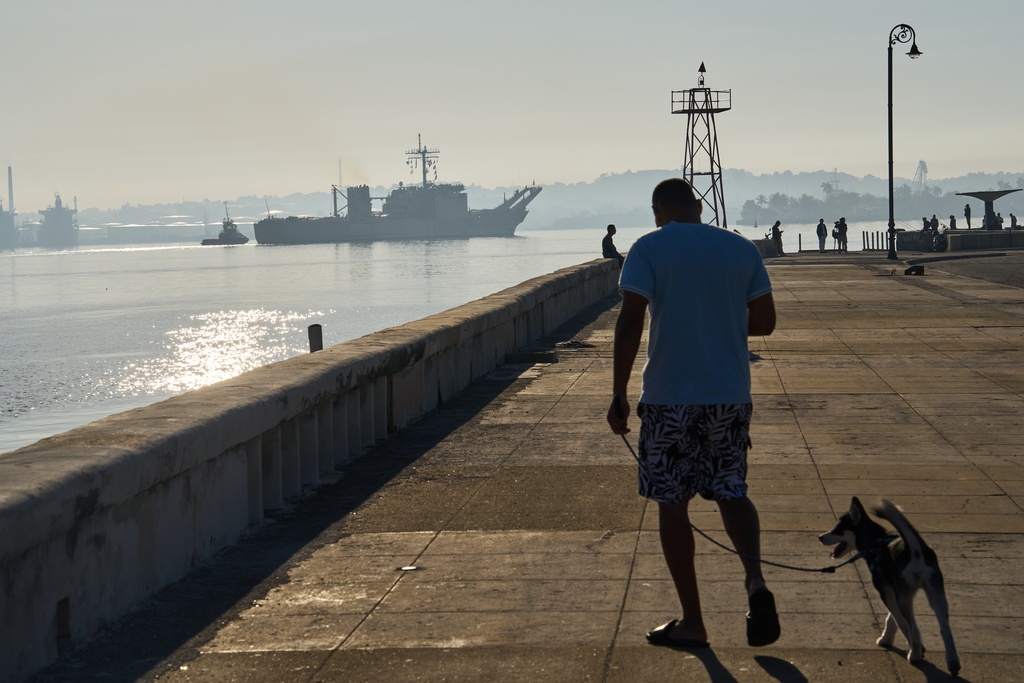 A man walks his dog along Havana Bay where the Mexican Navy ship Papaloapan, carrying aid according to the Mexican government, arrives in Cuba, Thursday, Feb. 12, 2026. (AP Photo/Ramon Espinosa)