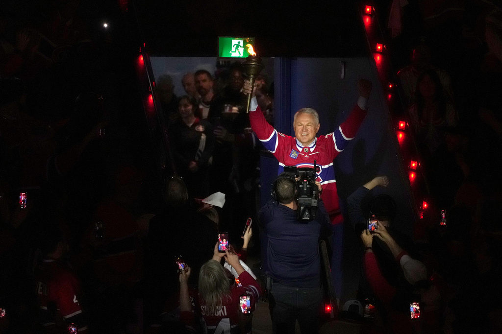 FILE - Former Montreal Canadiens player Claude Lemieux holds a torch as he enters the arena before Game 3 of the NHL Eastern Conference final Stanley Cup playoff series between the Canadiens and Carolina Hurricanes, Monday, May 25, 2026, in Montreal. (Christinne Muschi/The Canadian Press via AP, File)