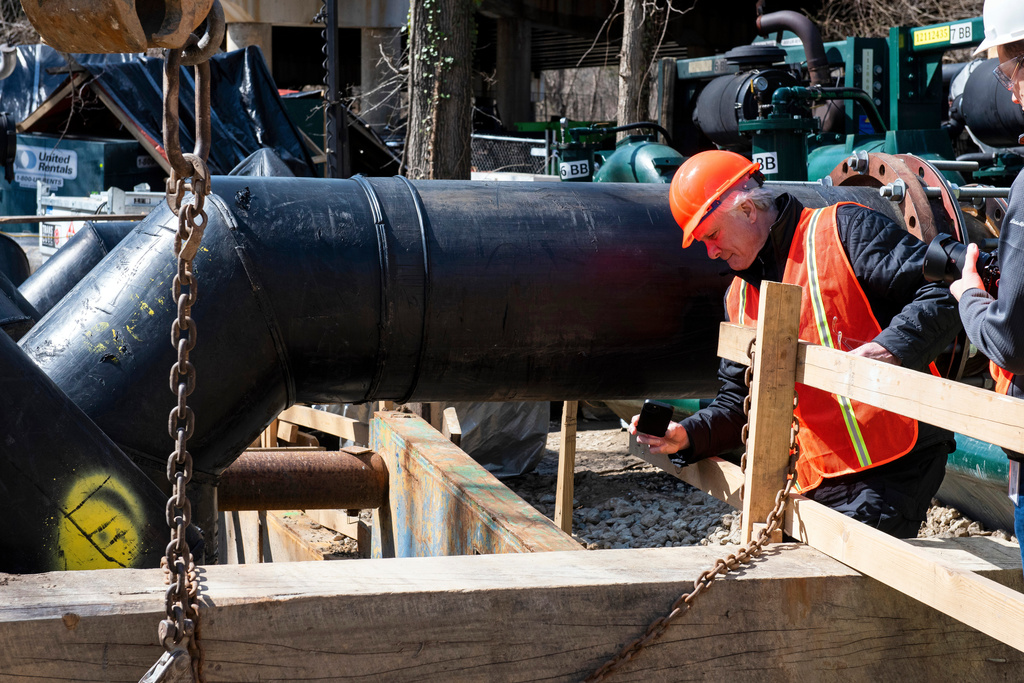 Noel Boxer, an external affairs officer with FEMA, inspects the flow of raw sewage, after a gate was raised to resume the flow, along the Potomac River, in Cabin John, Md., Saturday, March 14, 2026. (AP Photo/Cliff Owen)
