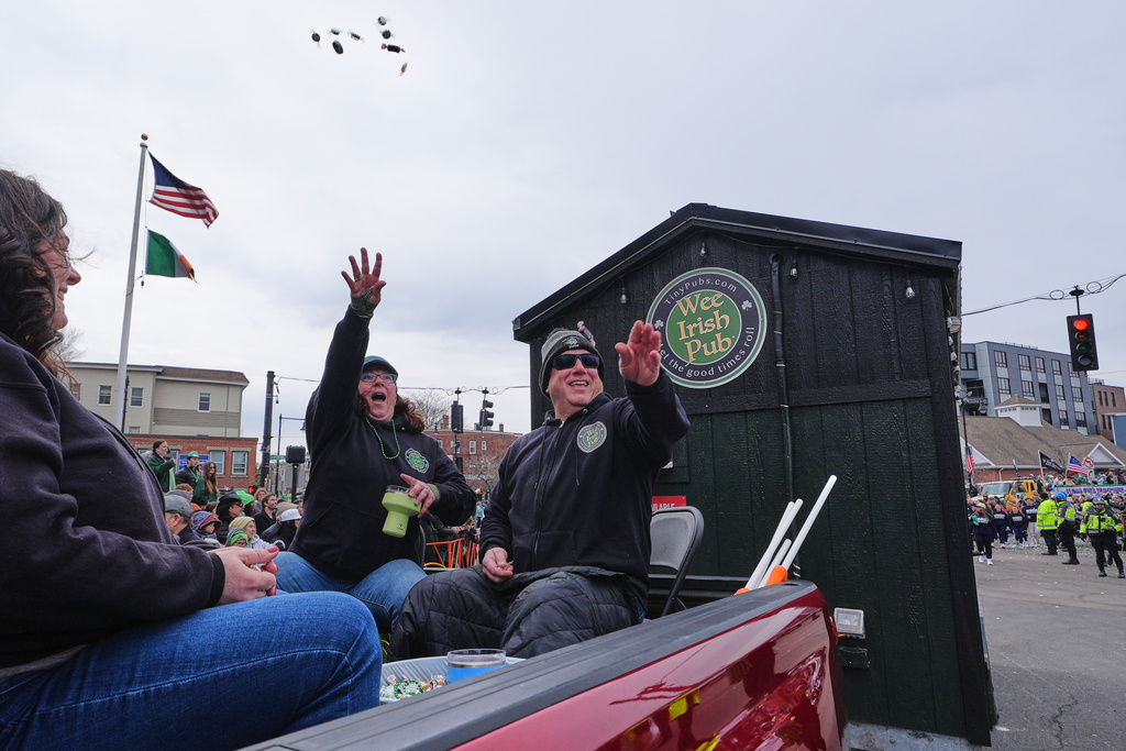 Dena Taylor and Tony DiDonato, right, toss candy to spectators while riding in a truck hauling the "Wee Irish Pub", a fully functioning mobile Irish pub built by two Massachusetts' brothers, during the annual St. Patrick's Day parade through the South Boston neighborhood, Sunday, March 15, 2026. (AP Photo/Charles Krupa)