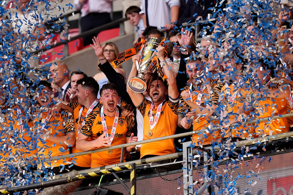 Hull City's Lewis Coyle lifts the trophy after winning promotion to the Premier League following the Championship play-off final between Hull City and Middlesbrough at Wembley Stadium, London, Saturday May 23, 2026. (Jordan Pettitt/PA via AP)