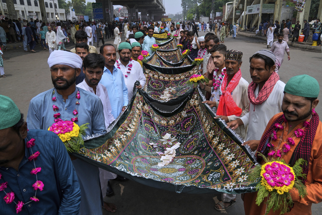 Devotees arrive with ceremonial cloth locally called 'chaddar' painted with 'Quranic recitations' which they place over the saint's grave during celebrations of the three-day annual festival or 'Urs' of mystic and scholar Hazrat Ali Hajveri, popularly known as Data Ganj Bakhsh at his shrine, in Lahore, Pakistan, Friday, Aug. 15, 2025. (AP Photo/K.M. Chaudary)