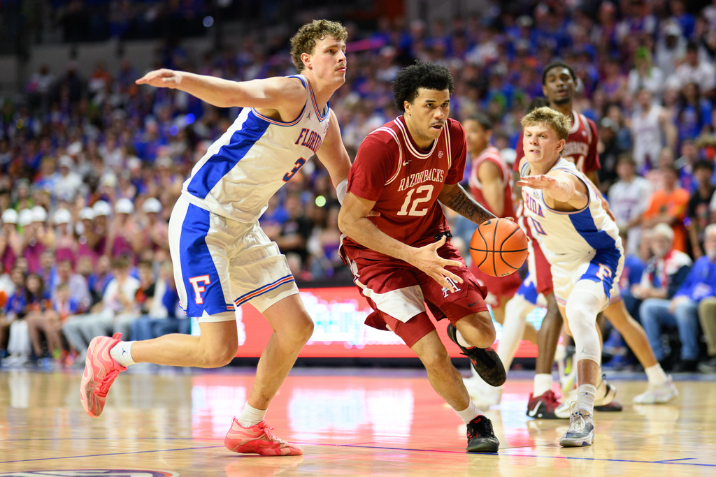 Arkansas forward Malique Ewin (12) drives against Florida center Micah Handlogten (3) during the first half of an NCAA college basketball game, Saturday, Feb. 28, 2026, in Gainesville, Fla. (AP Photo/Noah Lantor)
