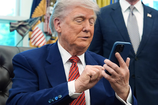 FILE - President Donald Trump silences his mobile phone in the Oval Office of the White House, May 23, 2025, in Washington. (AP Photo/Evan Vucci, File) FILE - President Donald Trump silences his mobile phone in the Oval Office of the White House, May 23, 2025, in Washington. (AP Photo/Evan Vucci, File)