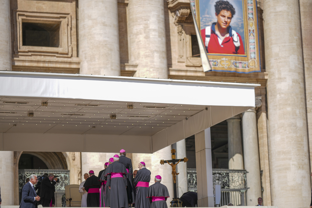Pope Leo XIV is greeted by Bishops in St. Peter's Square at the Vatican during an open-air jubiliar audience Saturday, Sept. 6, 2025, a day ahead of the canonization of Carlo Acutis who's portrait is hanging at top right. (AP Photo/Andrew Medichini)