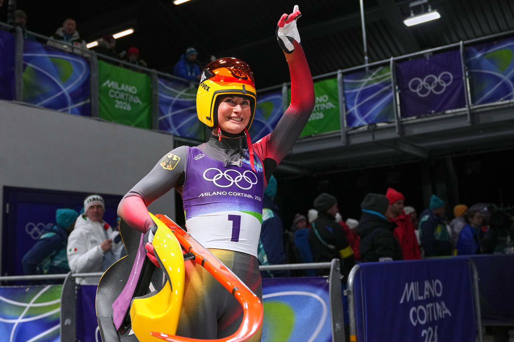 Germany's Julia Taubitz waves as she arrives at the finish during a women's single luge run at the 2026 Winter Olympics, in Cortina d'Ampezzo, Italy, Monday, Feb. 9, 2026. (AP Photo/Alessandra Tarantino)