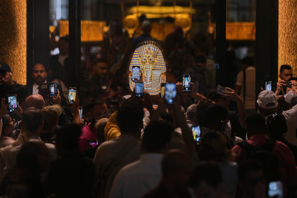 People hold mobile devices in front of the golden burial mask of King Tutankhamun during the first day for visitors after the official opening of the Grand Egyptian Museum in Giza, Egypt, Tuesday, Nov. 4, 2025. (AP Photo/Amr Nabil)