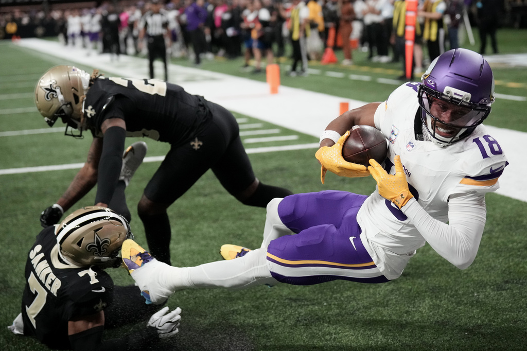 Minnesota Vikings wide receiver Justin Jefferson (18) catches a touchdown pass against New Orleans Saints safety Jonas Sanker (7) and cornerback Quincy Riley during the second half of an NFL football game in New Orleans, Sunday, Oct. 11, 2026. (AP Photo/Matthew Hinton)