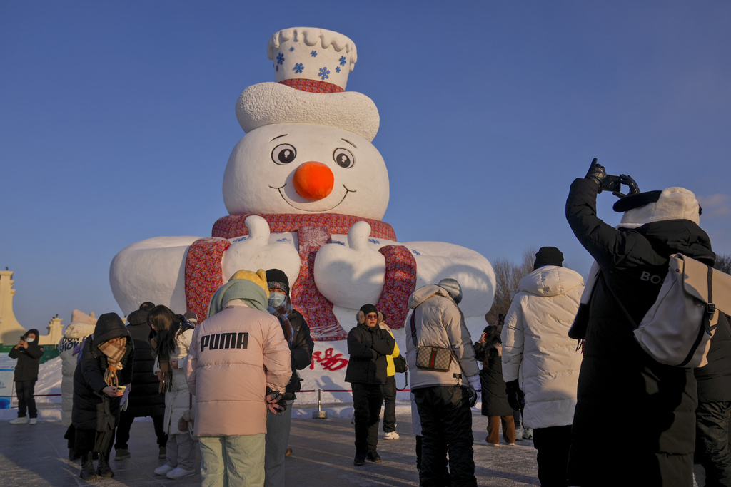 Visitors gather to take picture of a giant snowman on display at the Sun Island Park during the Harbin Ice and Snow World in Harbin, China's Heilongjiang province on Wednesday, Jan. 8, 2025. (AP Photo/Andy Wong)
