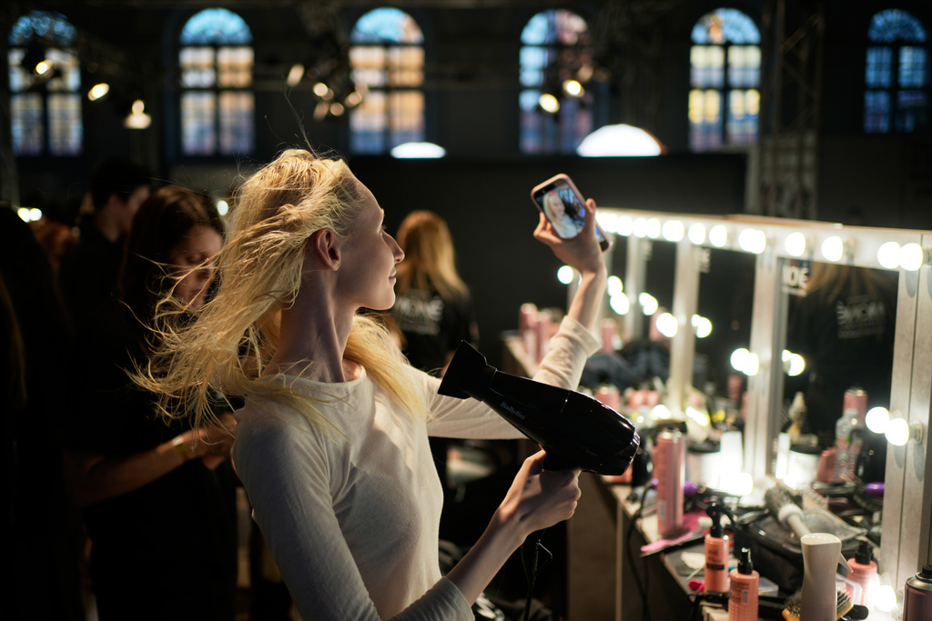 A model dries her hair backstage during Moscow Fashion Week in Moscow, Thursday, March 19, 2026. (AP Photo/Pavel Bednyakov)
