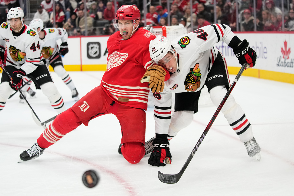 Detroit Red Wings left wing James van Riemsdyk, left, and Chicago Blackhawks defenseman Louis Crevier, right, vie for the puck during the second period of an NHL hockey game Sunday, Nov. 9, 2025, in Detroit. (AP Photo/Ryan Sun)