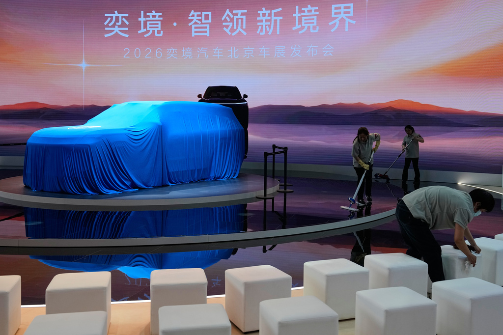Cleaners work near a covered Huawei new car model on stage as they prepare for the launch at the Auto China 2026, in Beijing, Friday, April 24, 2026. (AP Photo/Andy Wong)