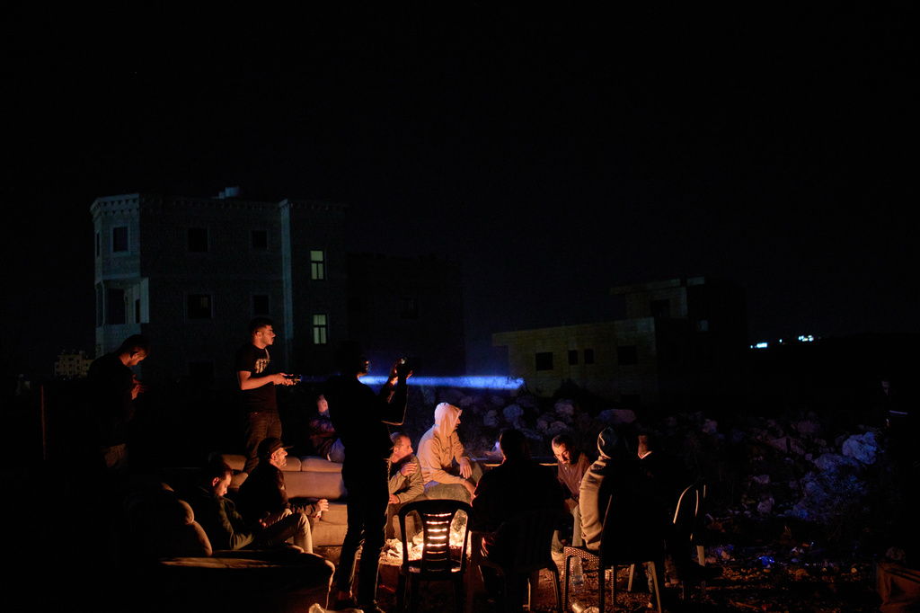A Palestinian uses a flashlight after spotting the presence of Israeli settlers on a hill as he takes part in a night watch with other volunteers to guard against settler attacks in the West Bank village of Sinjil, Thursday, July 16, 2026. (AP Photo/Leo Correa)