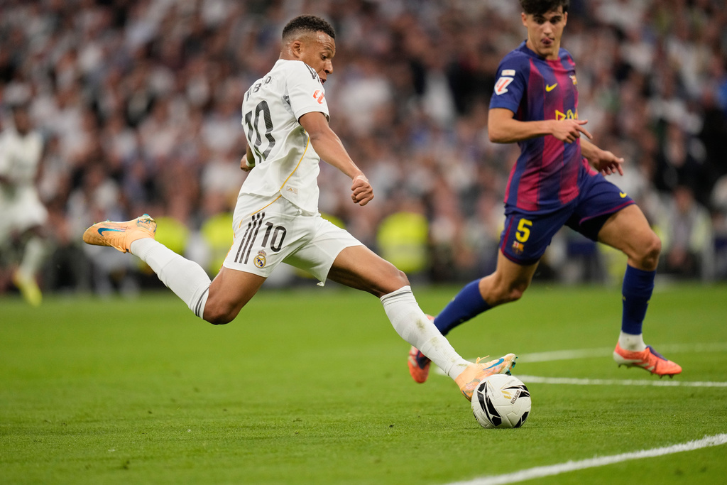 Real Madrid's Kylian Mbappe shoots by Barcelona's Pau Cubarsi during a La Liga soccer match between Real Madrid and Barcelona in Madrid, Spain, Sunday, Oct. 26, 2025. (AP Photo/Bernat Armangue)