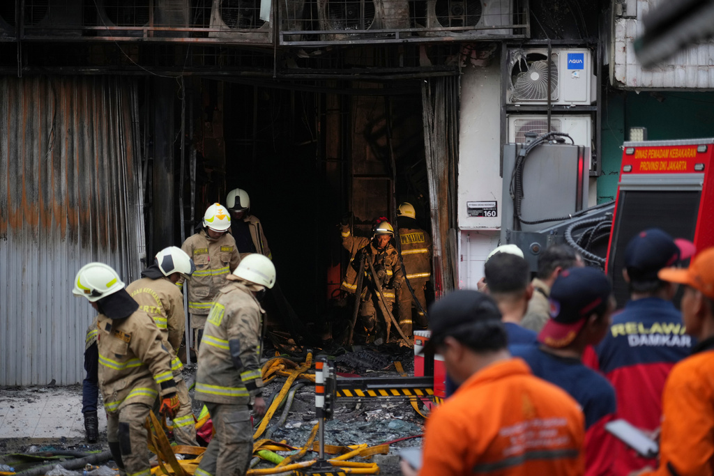 Firefighters work in an office building that caught fire in Jakarta, Indonesia, Tuesday, Dec. 9, 2025. (AP Photo/Dita Alangkara)