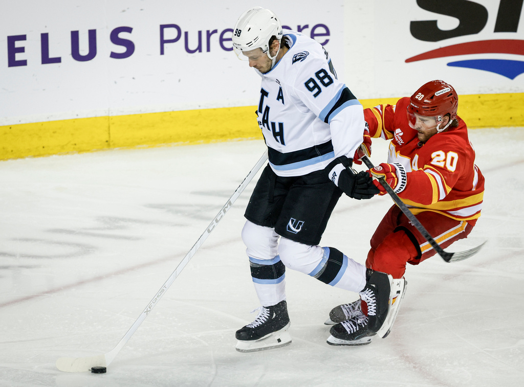 Utah Mammoth's Mikhail Sergachev, left, is checked by Calgary Flames' Blake Coleman during the third period of an NHL hockey game in Calgary on Sunday, April 12, 2026. (Jeff McIntosh/The Canadian Press via AP)
