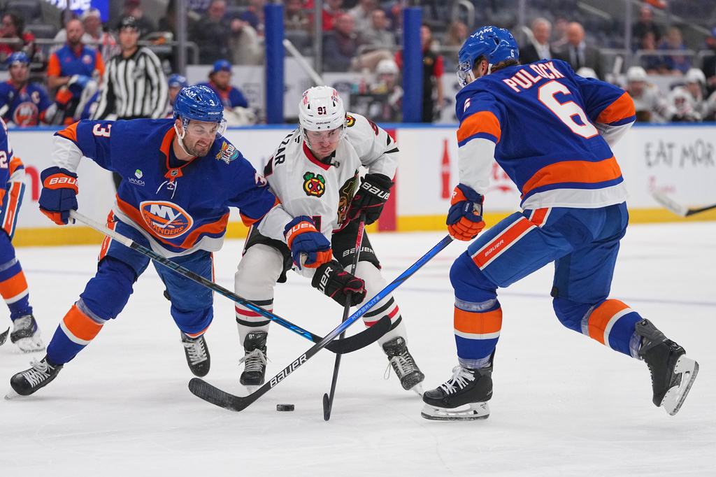 New York Islanders' Adam Pelech (3) and Ryan Pulock (6) fights for control of the puck with Chicago Blackhawks' Frank Nazar (91) during the first period of an NHL hockey game Thursday, Oct. 8, 2026, in Elmont, N.Y. (AP Photo/Frank Franklin II)