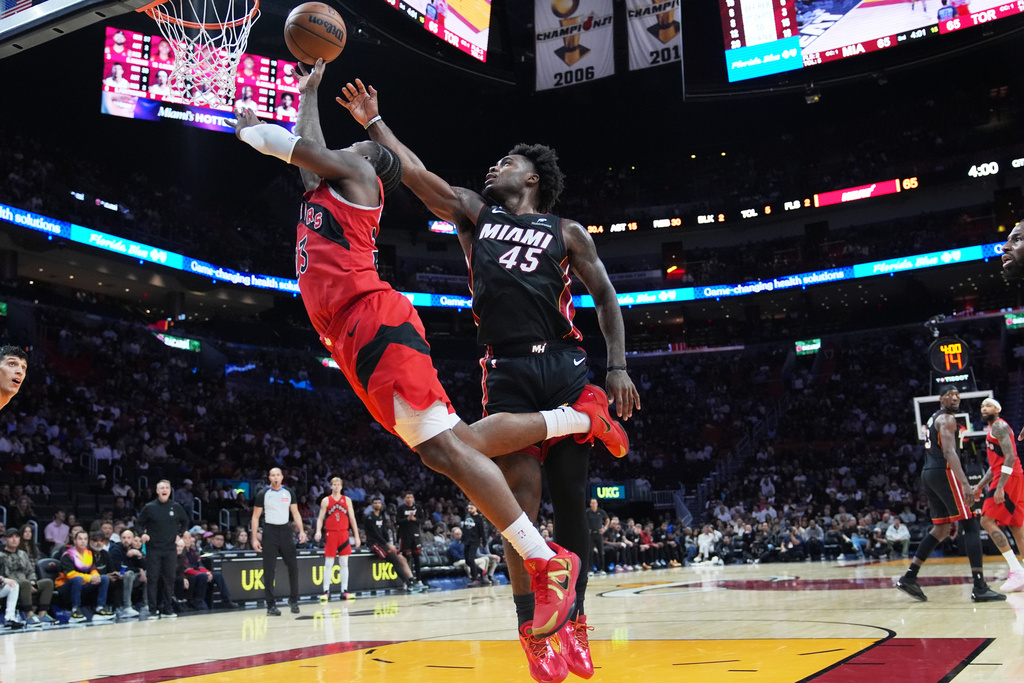 Toronto Raptors guard Jamal Shead, left, goes to the basket as Miami Heat guard Davion Mitchell (45) defends during the second half of an NBA basketball game, Monday, Dec. 15, 2025, in Miami. (AP Photo/Lynne Sladky)