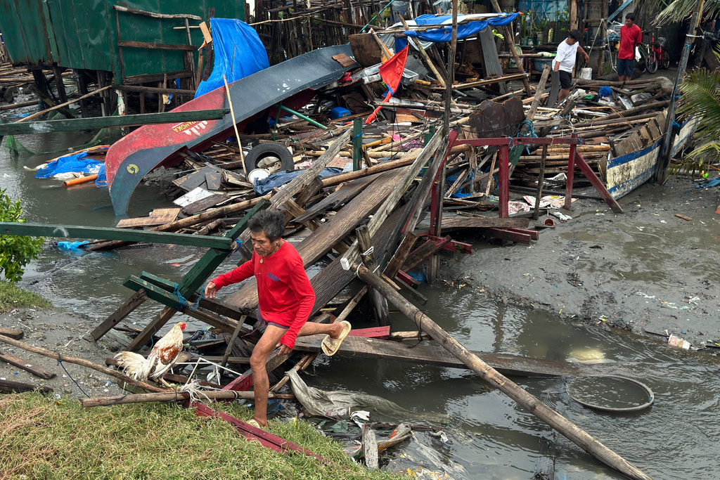 A man crosses a damaged bridge and house due to Typhoon Fung-wong along a coastal village on Monday, Nov. 10, 2025, in Navotas, Philippines. (AP Photo/Aaron Favila)