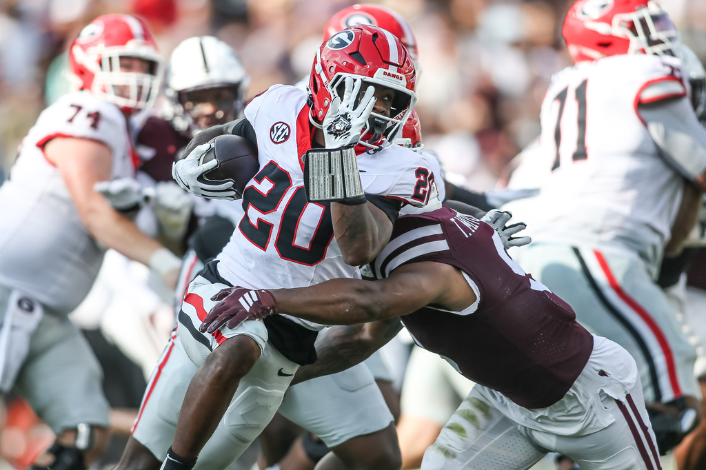 Georgia running back Dwight Phillips Jr. (20) tries to avoid a tackle against Mississippi State safety Tony Mitchell during the second half of an NCAA college football game in Starkville, Miss., Saturday, Nov. 8, 2025. (AP Photo/James Pugh)