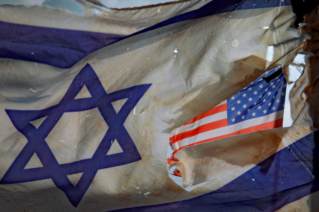 FILE- A U.S. flag is seen through a hole torn in an Israel national flag, as they wave in the wind at a horse ranch, near the southern Israeli town of Sderot, Friday, Nov. 20, 2020. (AP Photo/Oded Balilty, File)