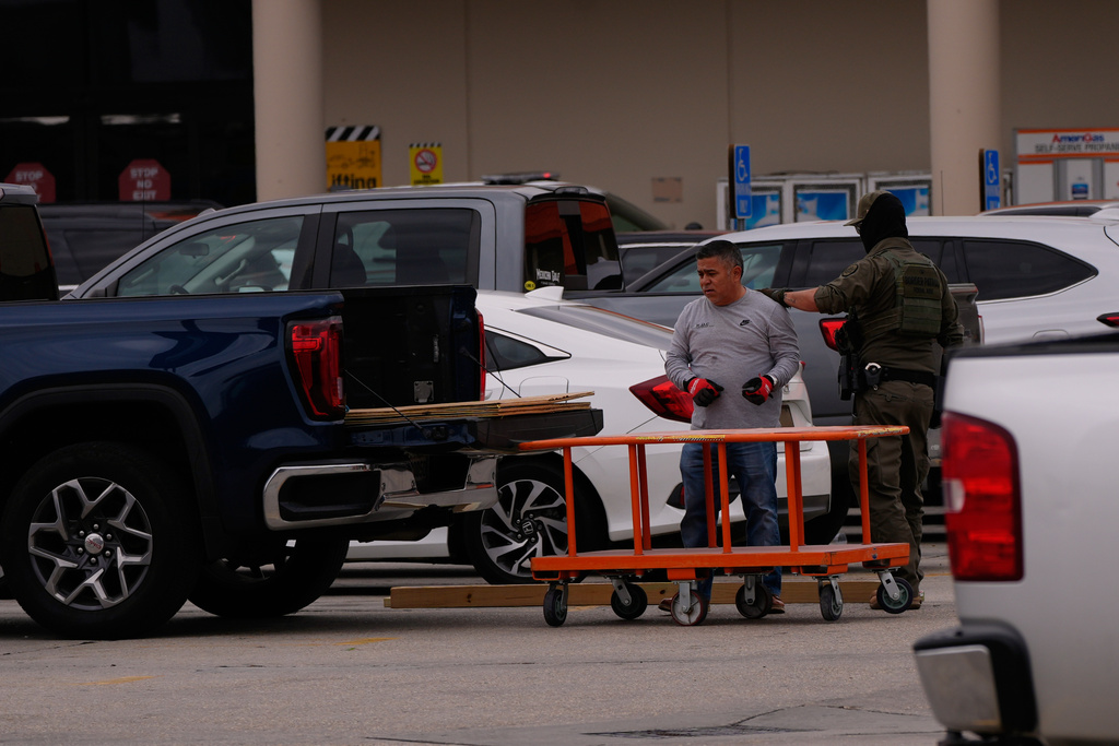U.S. Customs and Border Protection agents question a person at a Home Depot parking lot in Kenner, La.,Wednesday, Dec. 3, 2025. (AP Photo/Gerald Herbert)