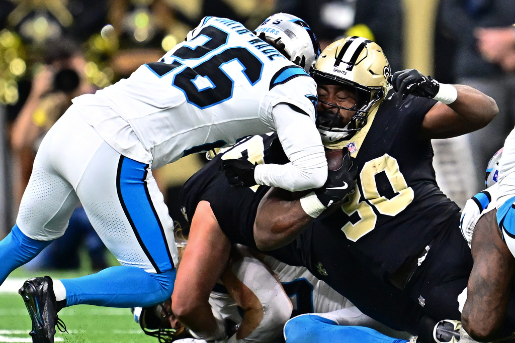 Carolina Panthers cornerback Chau Smith-Wade (26) tackles New Orleans Saints running back Audric Estimé (30) in the second half of an NFL football game, Sunday, Dec. 14, 2025, in New Orleans. (AP Photo/Ella Hall)