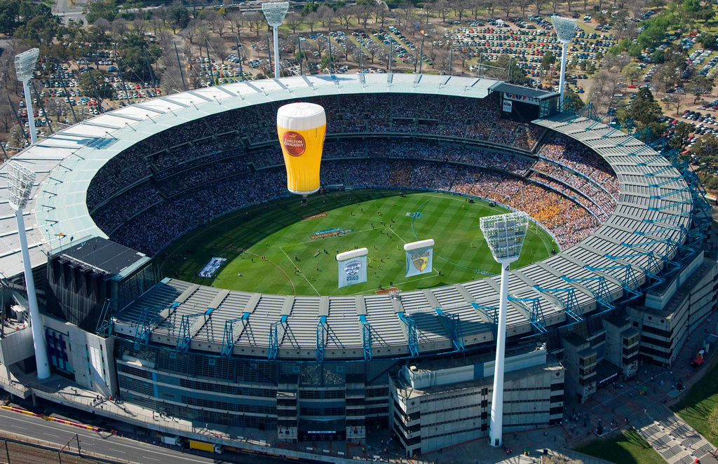 FILE - A hot air balloon shaped as a drinking glass flies over the Melbourne Cricket Ground in Melbourne, Australia, on Sept. 27, 2008. (AP Photo/Andrew Chapman, File)