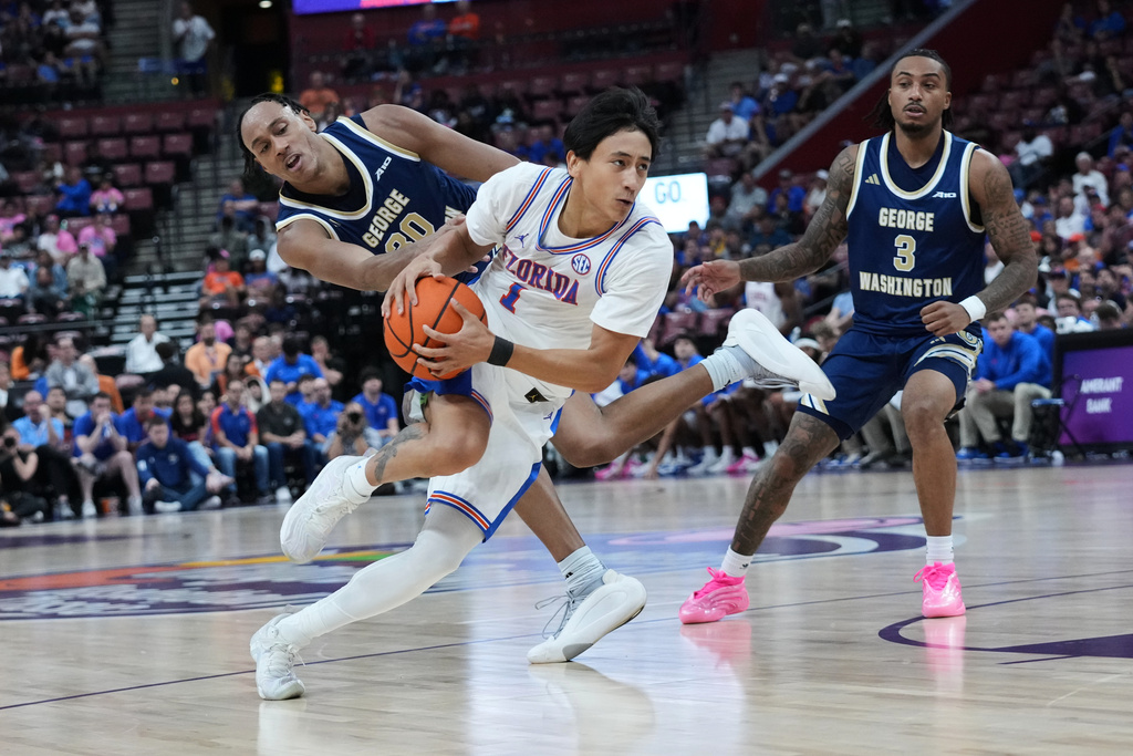 Florida guard Xaivian Lee (1) drives to the basket as George Washington forward Rafael Castro, left, defends during the first half of an NCAA college basketball game at the Orange Bowl Basketball Classic, Saturday, Dec. 13, 2025, in Sunrise, Fla. (AP Photo/Lynne Sladky)