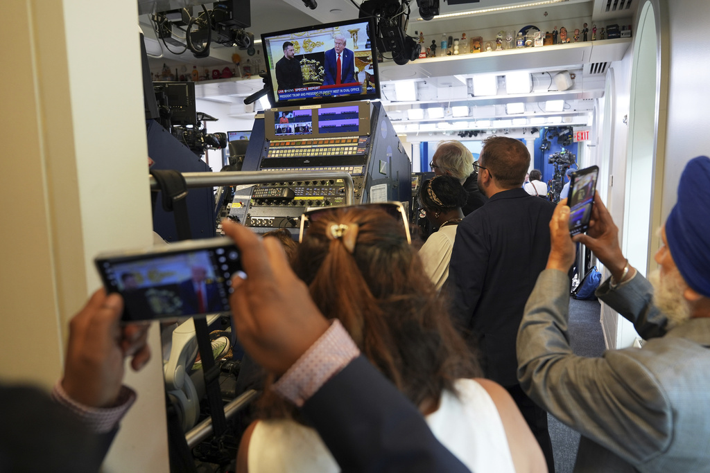 Members of the media watch a live feed as President Donald Trump, pictured on screen at right, meets with Ukraine's President Volodymyr Zelenskyy, Monday, Aug. 18, 2025, at the White House in Washington. (AP Photo/Jacquelyn Martin)
