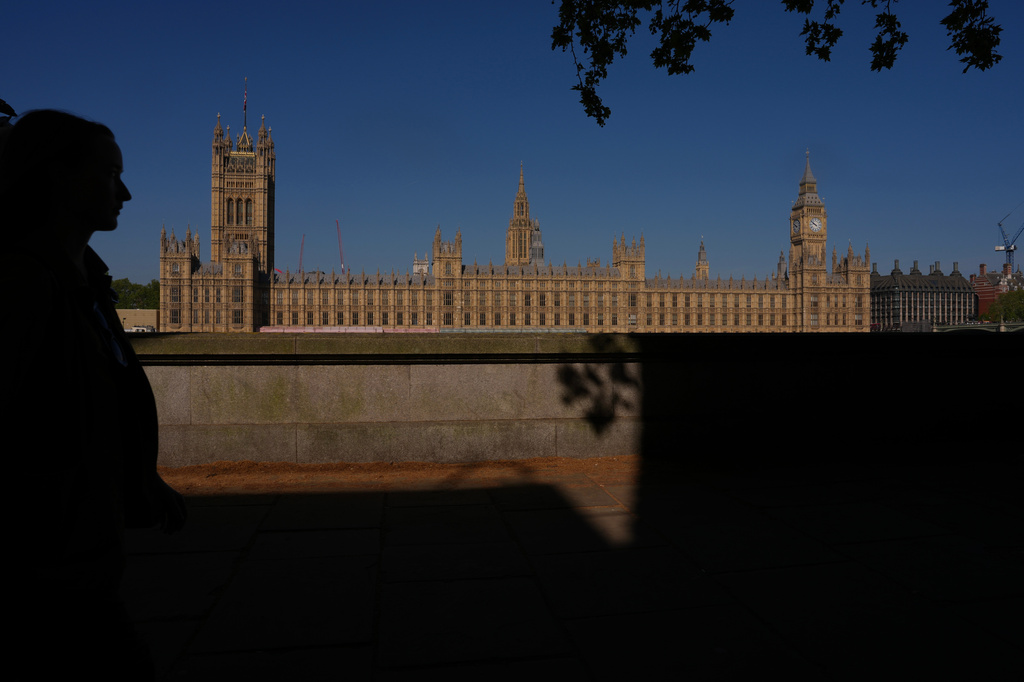 A woman walks past the Houses of Parliament in London, Monday, April 27, 2026. (AP Photo/Kin Cheung)