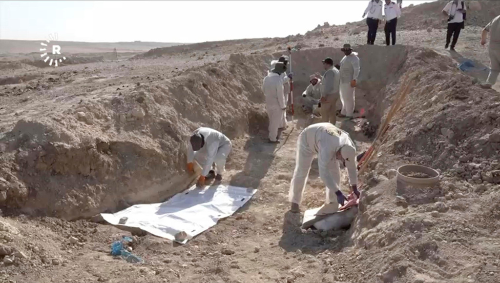 In this image taken from video provided by Rudaw TV, workers dig out human remains at the Khasfa site near the northern Iraqi city of Mosul, where authorities have begun excavating a mass grave believed to contain thousands of victims of the Islamic State (IS) Mosul, Iraq, Sunday, Aug. 17, 2025. (Rudaw TV via AP)