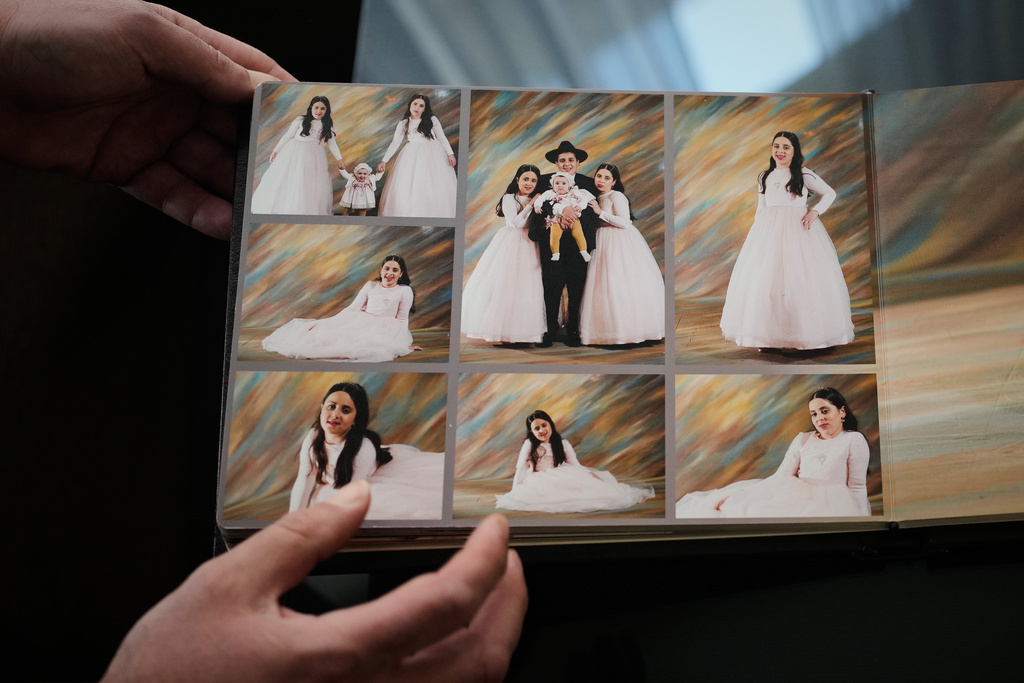 A relative shows photos of three siblings, Yaakov Biton and his two sisters, Avigail and Sarah, who were killed earlier this week when an Iranian missile struck their home in the city of Beit Shemesh, Jerusalem, Thursday, March 5, 2026. (AP Photo/Ohad Zwigenberg)