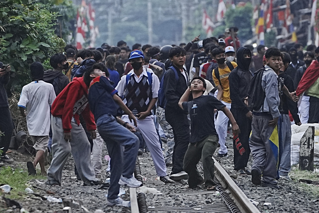 Protesters throw rocks towards riot police during a protest against lavish allowances given to parliament members, in Jakarta, Indonesia, Monday, Aug. 25, 2025. (AP Photo/Achmad Ibrahim)