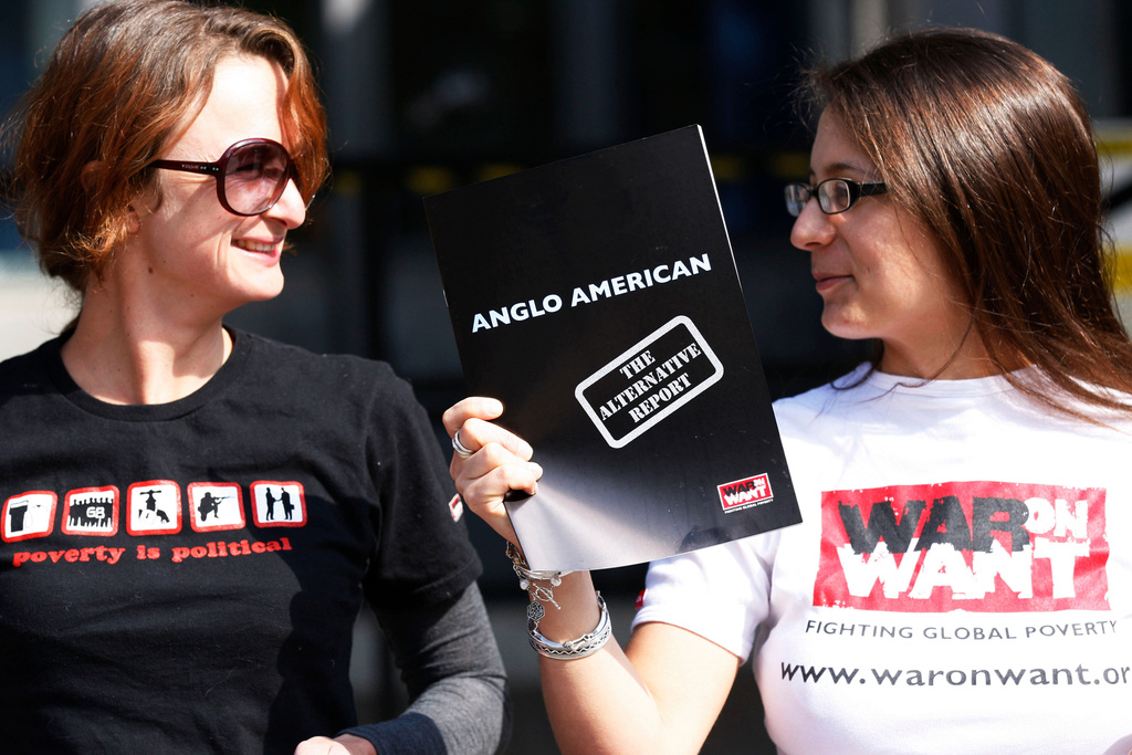 FILE - Human rights campaigners hold up an alternative report in a protest, over claimed of human rights abuse by Anglo American South Africa Ltd, outside the Queen Elizabeth II Conference Center in London where the British mining company Anglo American annual meeting is being held, Thursday, April 22, 2009. (AP Photo/Sang Tan, File)