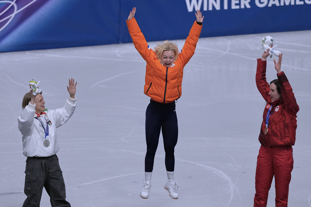 From left to right, silver medalist Arianna Fontana of Italy, gold medalist Xandra Velzeboer of the Netherlands and bronze medalist Courtney Sarault of Canada jump on the podium to receive their medals after the short track speed skating women's 500m at the 2026 Winter Olympics, in Milan, Italy, Thursday, Feb. 12, 2026. (AP Photo/Stephanie Scarbrough)