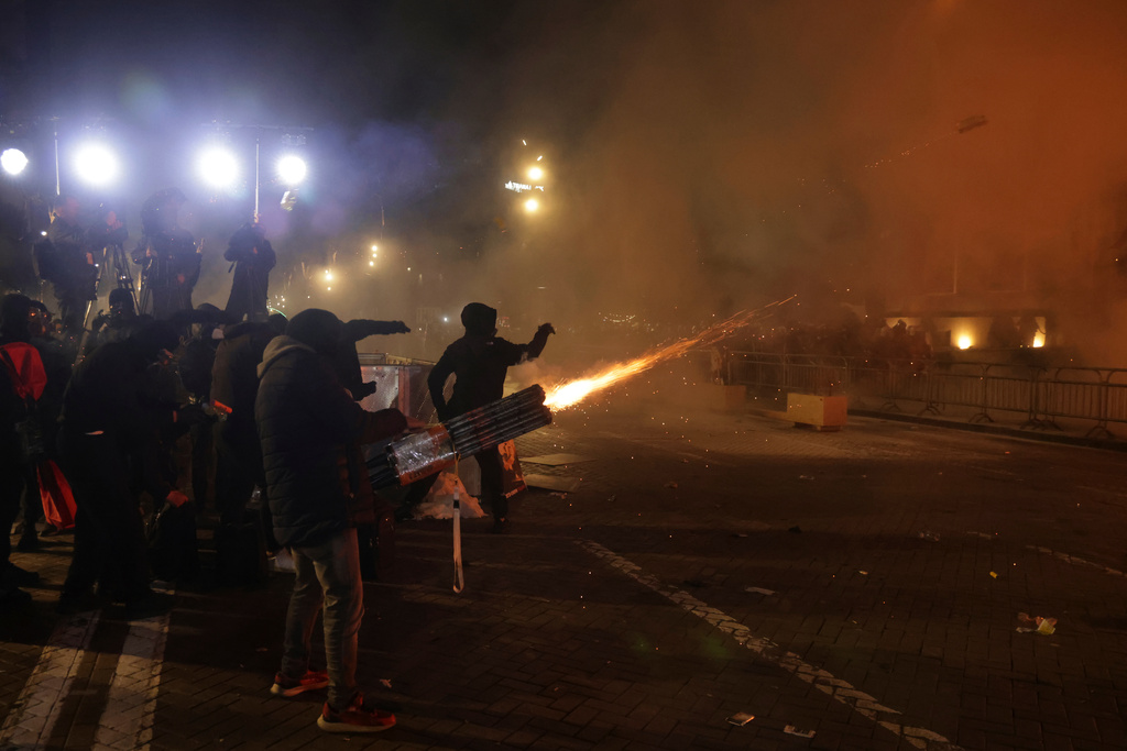 Hooded youth protesters throw flares and fireworks during an anti-government rally outside Prime Minister's office over corruption scandals and broader political issues, in Tirana, Albania, Tuesday, Feb. 10, 2026. (AP Photo/Hameraldi Agolli)