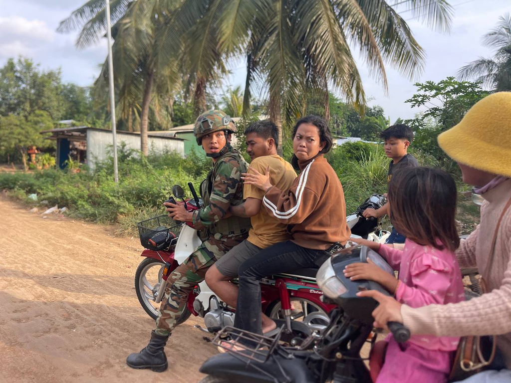 In this photo released by Agence Kampuchea Press (AKP), an injured man, second from right, is picked up by a Cambodian army soldier on a motorbike after Thai soldiers opened fire on civilians in Prey Chan village, Banteay Meanchey province, on the border with Thailand, Wednesday, Nov. 12, 2025. (AKP via AP)