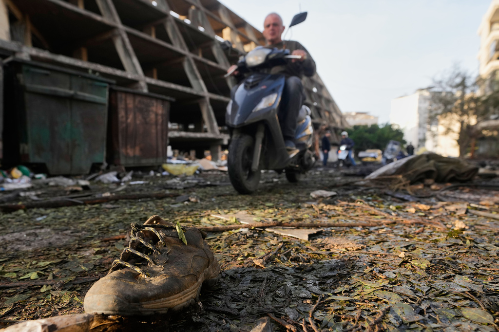 A shoe lies amid debris as a man rides a scooter past the site of an Israeli strike in Beirut, Lebanon, Wednesday, April 1, 2026. (AP Photo/Hassan Ammar)
