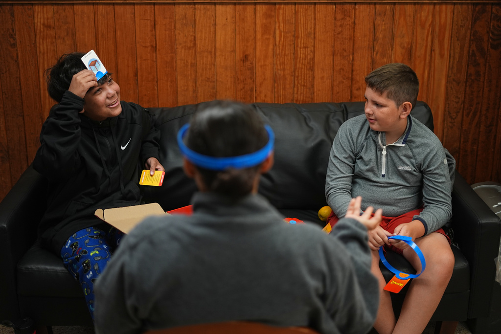Dylan Aristy Mota, 12, left, and Ethan Blanchfield-Killeen, right, 11, play a game with Nurse Mary Ramos ahead of their examination at the wellness center at the Frost Valley YMCA sleepaway camp in Claryville, N.Y., Thursday, July 31, 2025. The camp partnered with Children's Hospital at Montefiore so kids with autoimmune diseases could attend for the first time. (AP Photo/Matt Rourke)