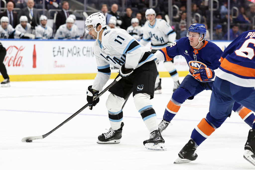 Utah Mammoth right wing Dylan Guenther (11) controls the puck past New York Islanders center Kyle MacLean in the third period of an NHL hockey game, Thursday, Jan. 1, 2026, in Elmont, N.Y. (AP Photo/Adam Hunger)