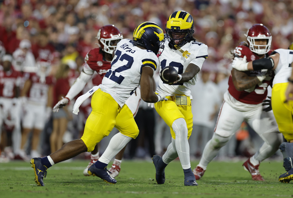Michigan quarterback Bryce Underwood, center right, hands off the ball to running back Justice Haynes (22) during the first half of an NCAA college football game against Oklahoma, Saturday, Sept. 6, 2025, in Norman, Okla. (AP Photo/Alonzo Adams)
