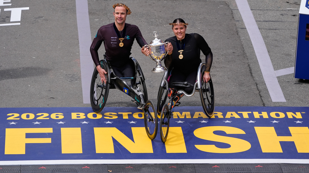 Men's wheelchair division winner Marcel Hug, of Switzerland, left, and women's wheelchair division winner Eden Rainbow-Cooper, of Portsmouth, England, hold the trophy after competing in the Boston Marathon, Monday, April 20, 2026, in Boston. (AP Photo/Charles Krupa)