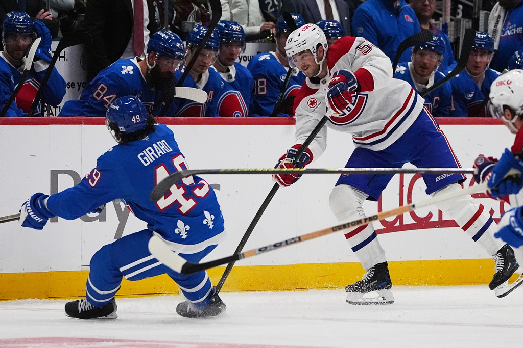 Montreal Canadiens defenseman Noah Dobson (53) passes the puck past Colorado Avalanche defenseman Samuel Girard (49) in the second period of an NHL hockey game Saturday, Nov. 29, 2025, in Denver. (AP Photo/David Zalubowski)