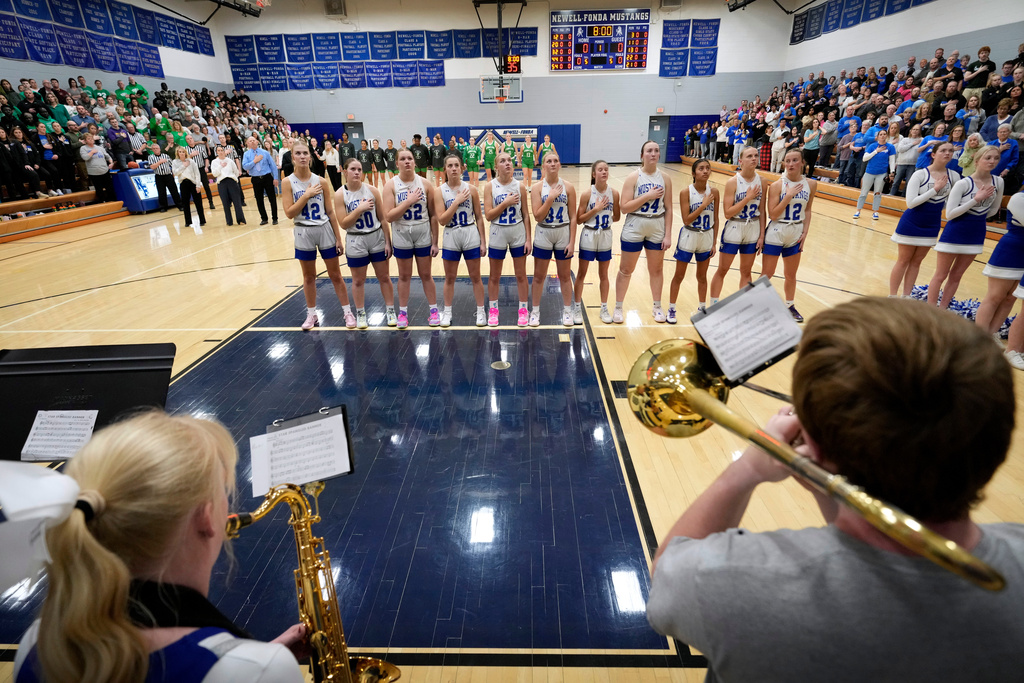 Newell-Fonda High School players stand for the national anthem before a girls basketball game against Storm Lake, Jan. 6, 2026, in Newell, Iowa. (AP Photo/Charlie Neibergall)