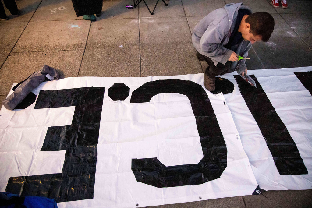 A protester paints a sign outside of the U.S. Immigration and Customs Enforcement facility in Portland, Ore. on Sunday, Oct. 5, 2025. (AP Photo/Ethan Swope)
