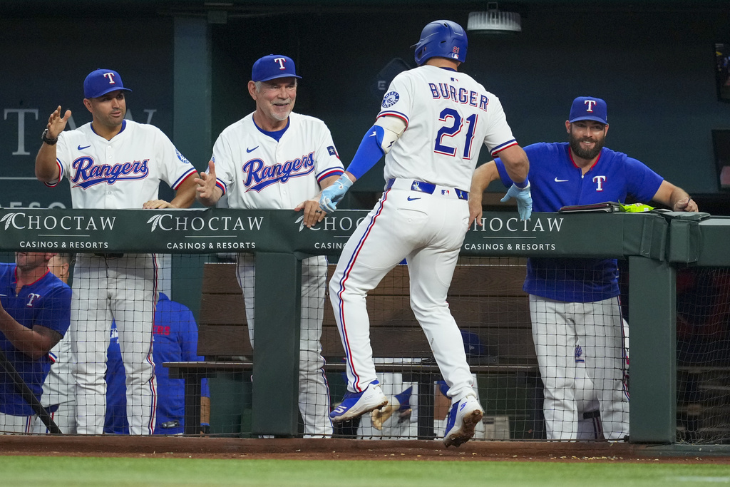 Texas Rangers' Jake Burger (21) is greeted near the dugout by bench coach Luis Urueta, left, manager Bruce Bochy, second from left, and hitting coach Justin Viele after hitting a solo home run off Milwaukee Brewers starting pitcher Freddy Peralta during the second inning of a baseball game Wednesday, Sept. 10, 2025, in Arlington, Texas. (AP Photo/Julio Cortez)