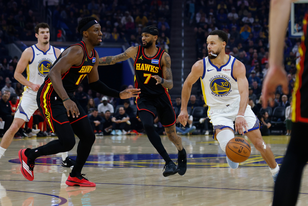 Golden State Warriors Stephen Curry (30) dribbles the ball past Atlanta Hawks Nickeil Alexander-Walker (7) during the first quarter of an NBA basketball game in San Francisco, Sunday, Jan. 11, 2026. (Carlos Avila Gonzalez/San Francisco Chronicle via AP)