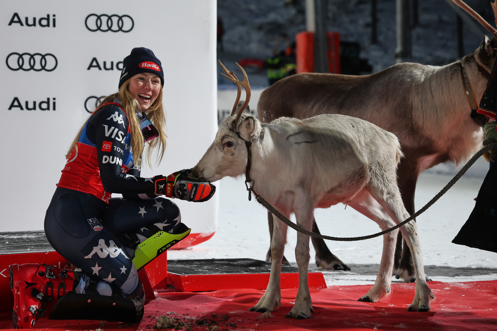 United States' Mikaela Shiffrin feeds a deer on the podium after winning an alpine ski, women's World Cup slalom, in Levi, Finland, Saturday, Nov. 15, 2025. (AP Photo/Marco Trovati)