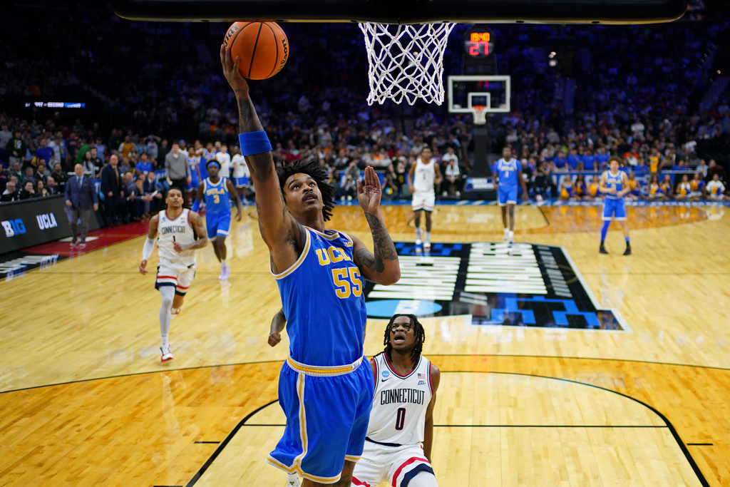 UCLA's Skyy Clark, left, goes up for a shot past UConn's Malachi Smith during the first half in the second round of the NCAA college basketball tournament, Sunday, March 22, 2026, in Philadelphia. (AP Photo/Matt Slocum)